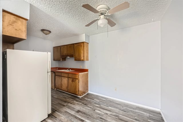 Kitchen area with refrigerator, wooden cabinets, and laminate flooring