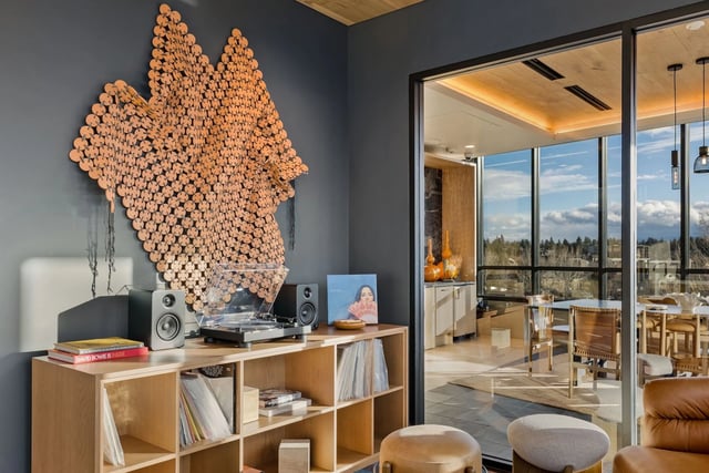 Contemporary living room with wall sculpture, vinyl setup, and glass door to sunlit balcony.