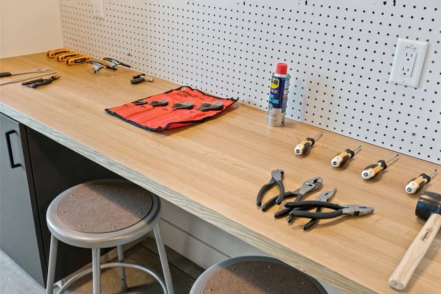 Tool-filled workbench with pegboard in a maintenance room.