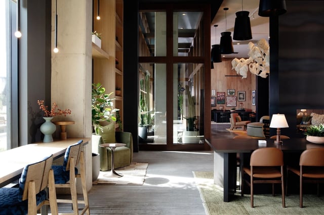 Modern apartment lobby with seating, plants, and glass doors.