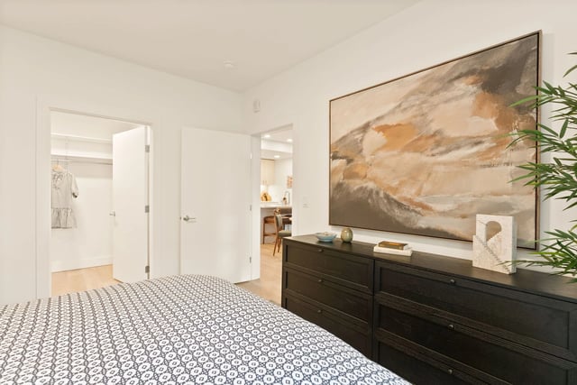 Bedroom with a dark dresser, large abstract painting, and an open closet.