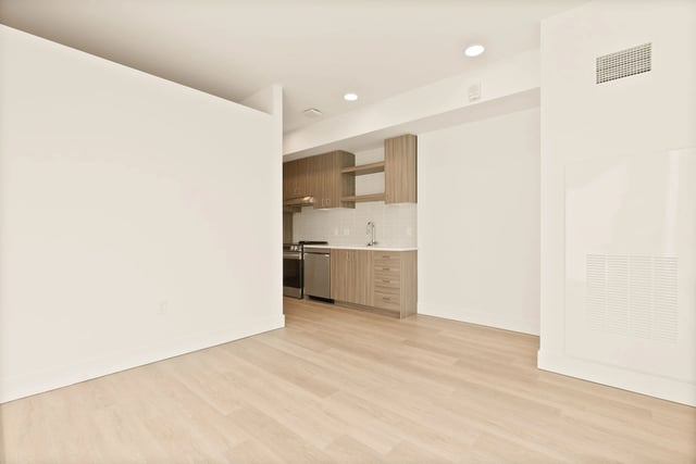 Open-plan kitchen with wood cabinets, stainless steel appliances, and light wood floors.