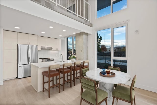 Bright open-concept kitchen with stainless steel appliances, an island, and a marble dining table.