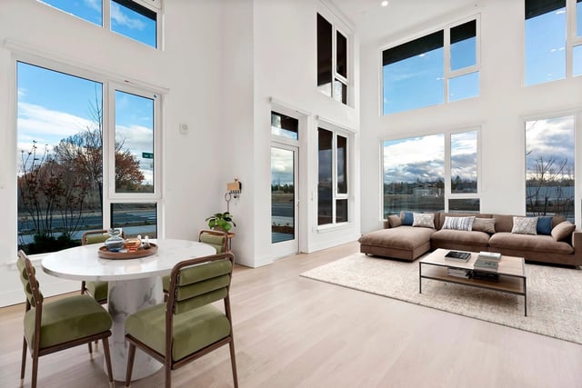 Bright living room with tall ceilings, large windows, white walls, and a beige sectional sofa.