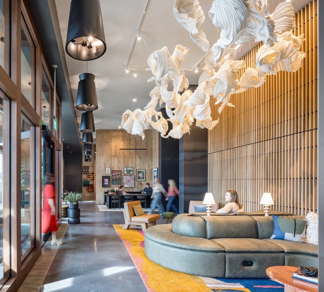 Interior view of a modern apartment lobby with a curved sectional and sculptural ceiling.