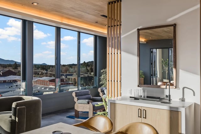 Bright modern apartment interior with a kitchenette, seating area, and large windows with city views.