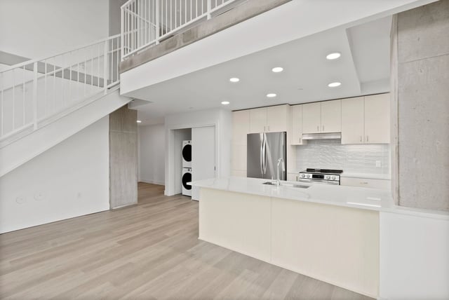 Open-concept kitchen with island, white cabinets, and stainless-steel appliances.