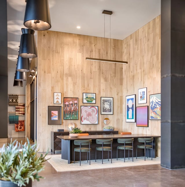 Contemporary resident lounge with a long communal table, wall art, and pendant lighting.