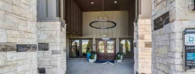 Exterior view of the property's building entrance with stone facade and modern chandelier.