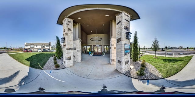 The exterior entrance to a multifamily property with stone pillars and a modern chandelier.