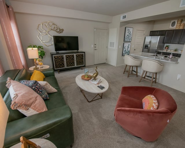 A living room with a green couch, a red chair, and a coffee table.