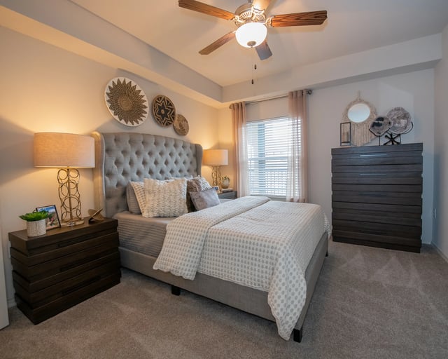 A bedroom with a large bed and a ceiling fan.