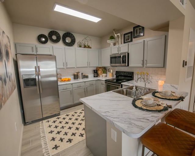 A kitchen with a marble countertop and a refrigerator.