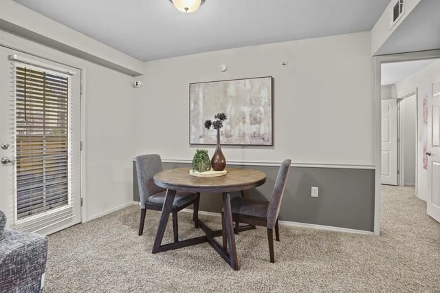 Interior dining area with a round wooden table and two gray chairs.