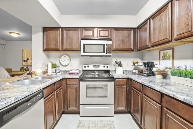 U-shaped kitchen with dark wood cabinets, granite countertops, and stainless steel stove and microwave.