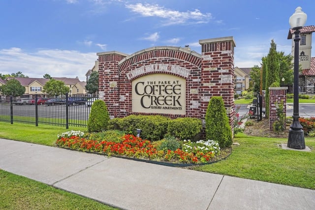 The Park at Coffee Creek luxury apartments monument sign with landscaping.