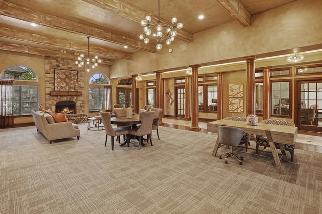 Community lounge area with fireplace, seating, dining table, and workspace.