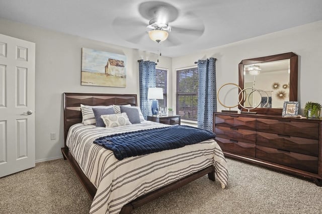 Cozy bedroom with a queen-size bed, dark wood dresser, and abstract art.