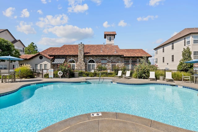 Resort-style swimming pool and lounge chairs with apartment buildings in the background.