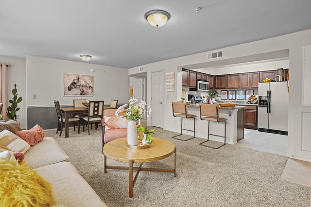 Open concept living and kitchen area with dining table, sofa, coffee table, and kitchen island with bar stools.