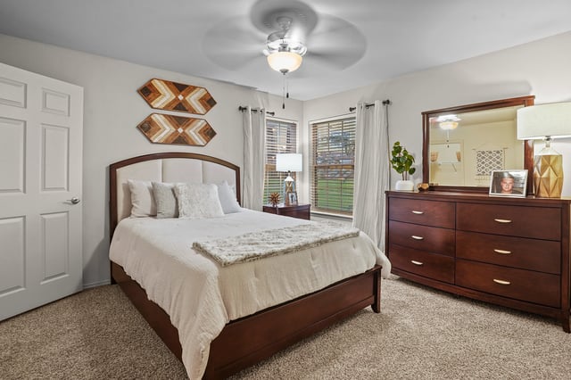 Spacious bedroom with a queen-size bed, dresser, and nightstand.