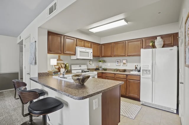 Kitchen in an apartment with wood cabinets, granite counters, and an island.