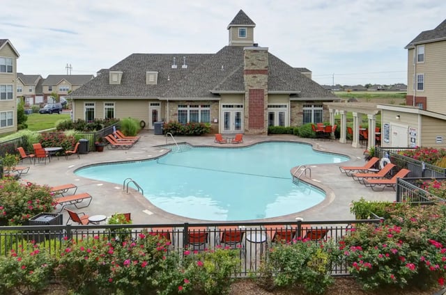 Outdoor apartment community pool with lounge chairs and surrounding landscaping