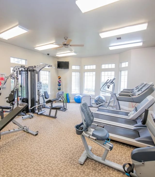 Interior view of a community gym with treadmills and weight machines.