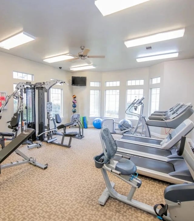 Bright interior of a community fitness center with treadmills, weight machines, and free weights.