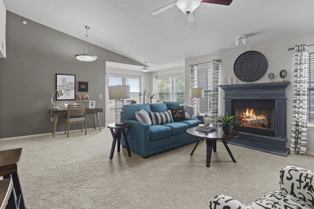 Living room with a teal sofa, fireplace, and a desk area.