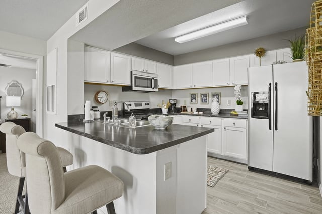 A kitchen with a black countertop and white cabinets.