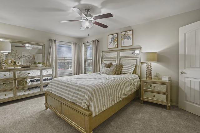 Bedroom with a queen-size bed, dresser, nightstand, and ceiling fan.