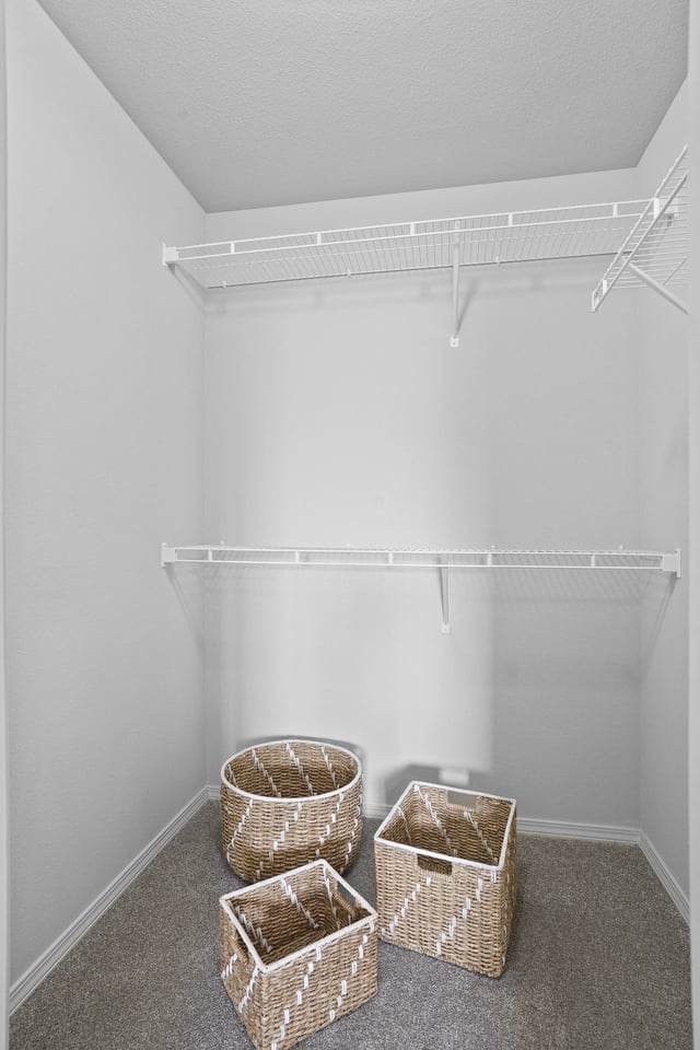 Empty closet with wire shelving and decorative baskets.