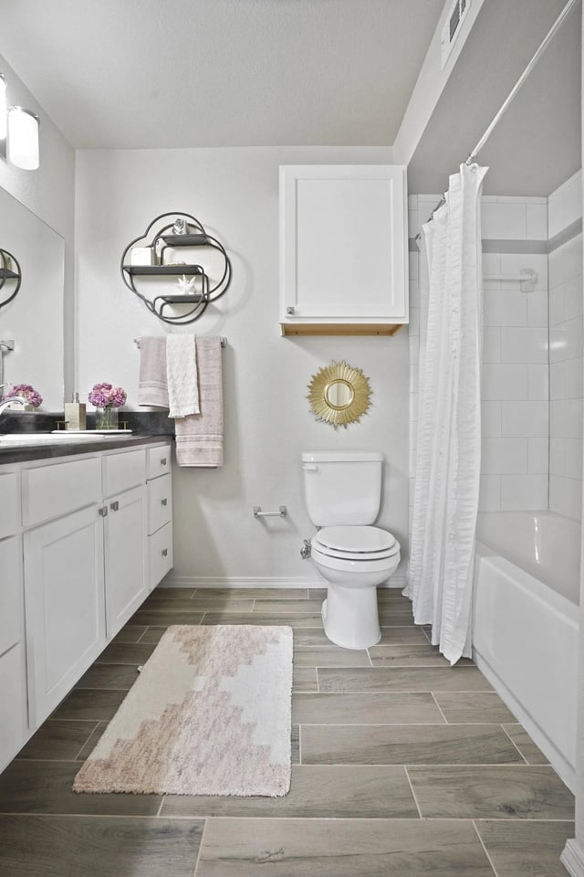 Modern bathroom with white vanity, toilet, and bathtub with white shower curtain.