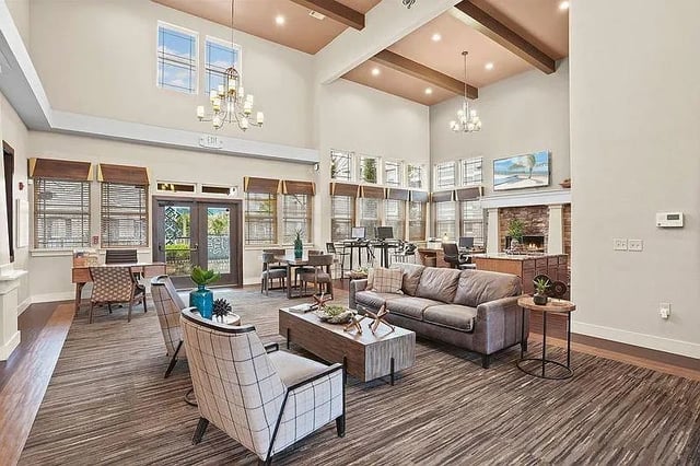 Comfortable seating area in a spacious apartment community lounge with a fireplace and computer stations.