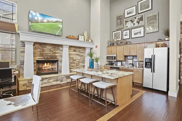 Open-concept living area with a stone fireplace, marble island, and stainless-steel appliances.
