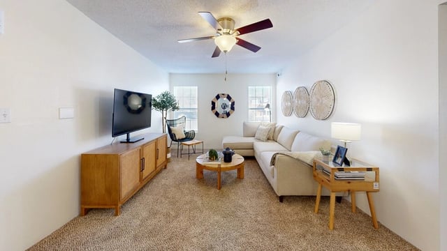 Living room with sectional sofa, coffee table, TV, and media console.