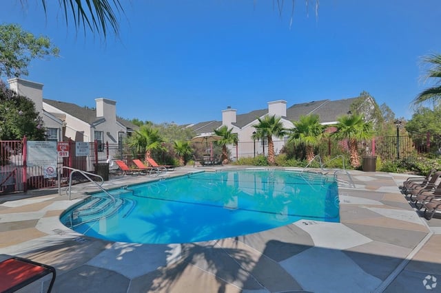 Resort-style swimming pool with lounge chairs and palm trees