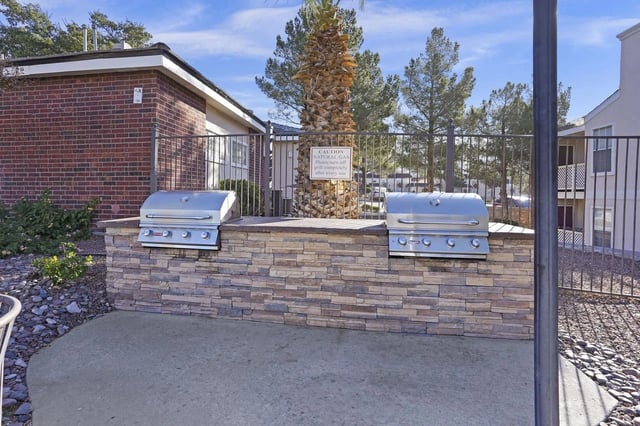 Outdoor communal grilling area with two built-in stainless steel grills and a stone counter.