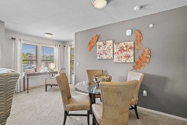 Dining area with a round glass table and four upholstered chairs.