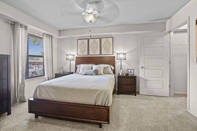 Cozy bedroom with a queen-size bed, nightstands, lamps, and ceiling fan.
