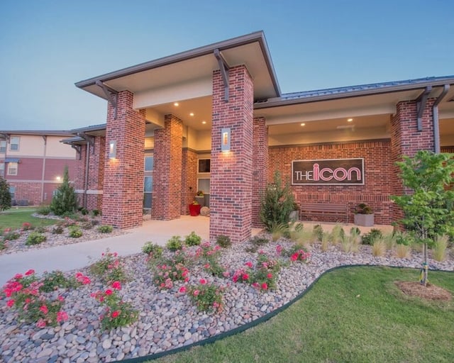 The Icon apartment building exterior entrance with brick facade and landscaping.