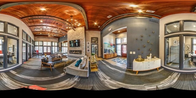 Spacious resident lounge with a stone fireplace, comfortable seating, and a modern chandelier.