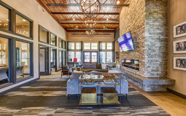 Modern lobby with stone fireplace, chandeliers, and comfortable seating.