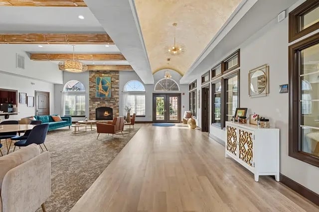 Spacious, modern community lobby with seating, a stone fireplace, and arched windows.