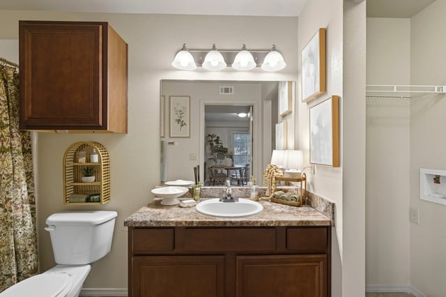 Bathroom vanity with sink, dark wood cabinets, and a mirror reflecting a dining area.