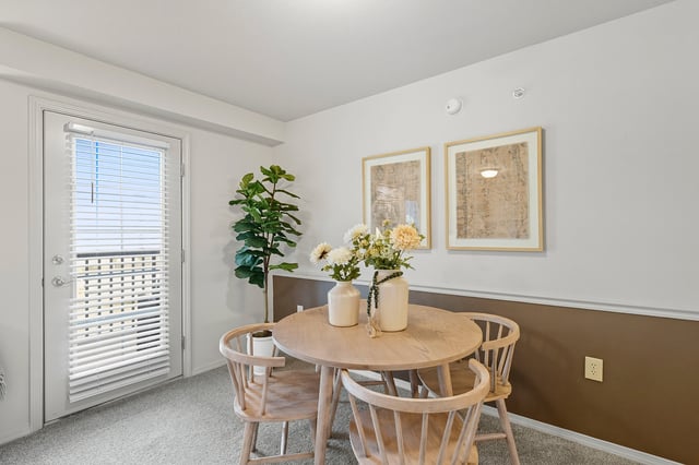 Dining area with a round wooden table, four chairs, and a plant.