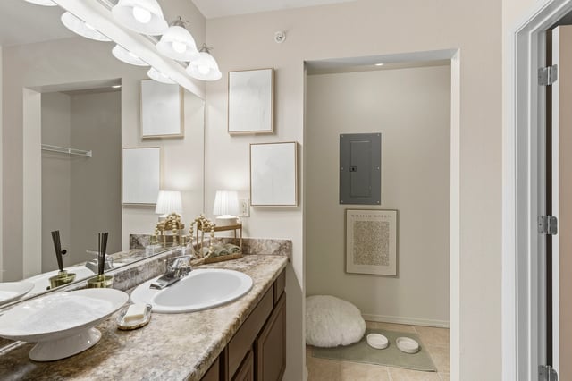 A bathroom vanity with a sink, marble countertops, and a large mirror.