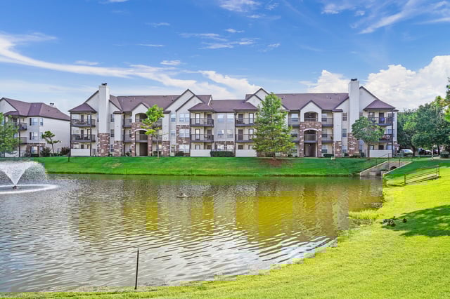 Apartment buildings overlooking a lake with a fountain and ducks.