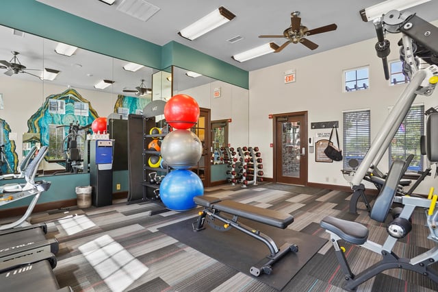 Interior of a well-equipped fitness center with cardio machines, free weights, and exercise balls.